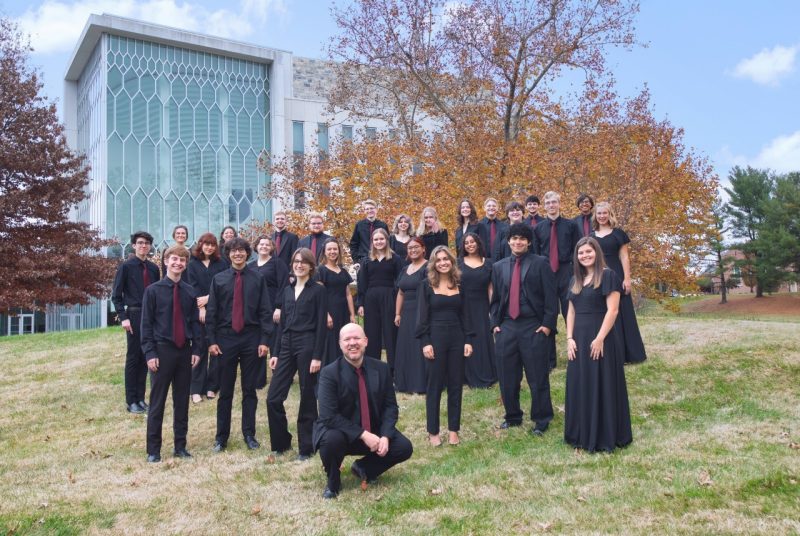 Virginia Tech Chamber Singers, dressed in black, stand in front of the Moss Arts Center on the campus of Virginia Tech