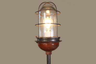 A ghost light, as used in the theatre, with a single light bulb surrounded in a cage