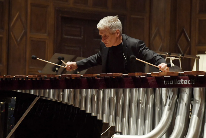 Michael Burritt A man playing a marimba, holding two mallets in each hand.