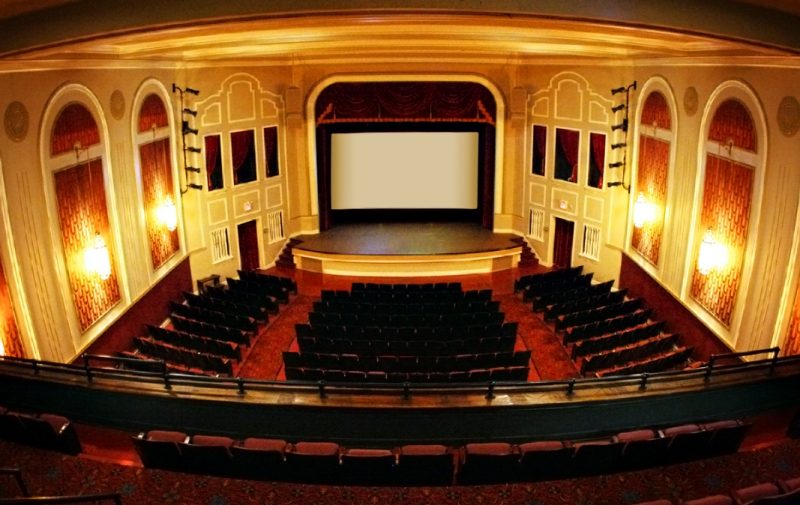 View from the inside of the Lyric Theatre with beige walls with white trim, facing the stage.